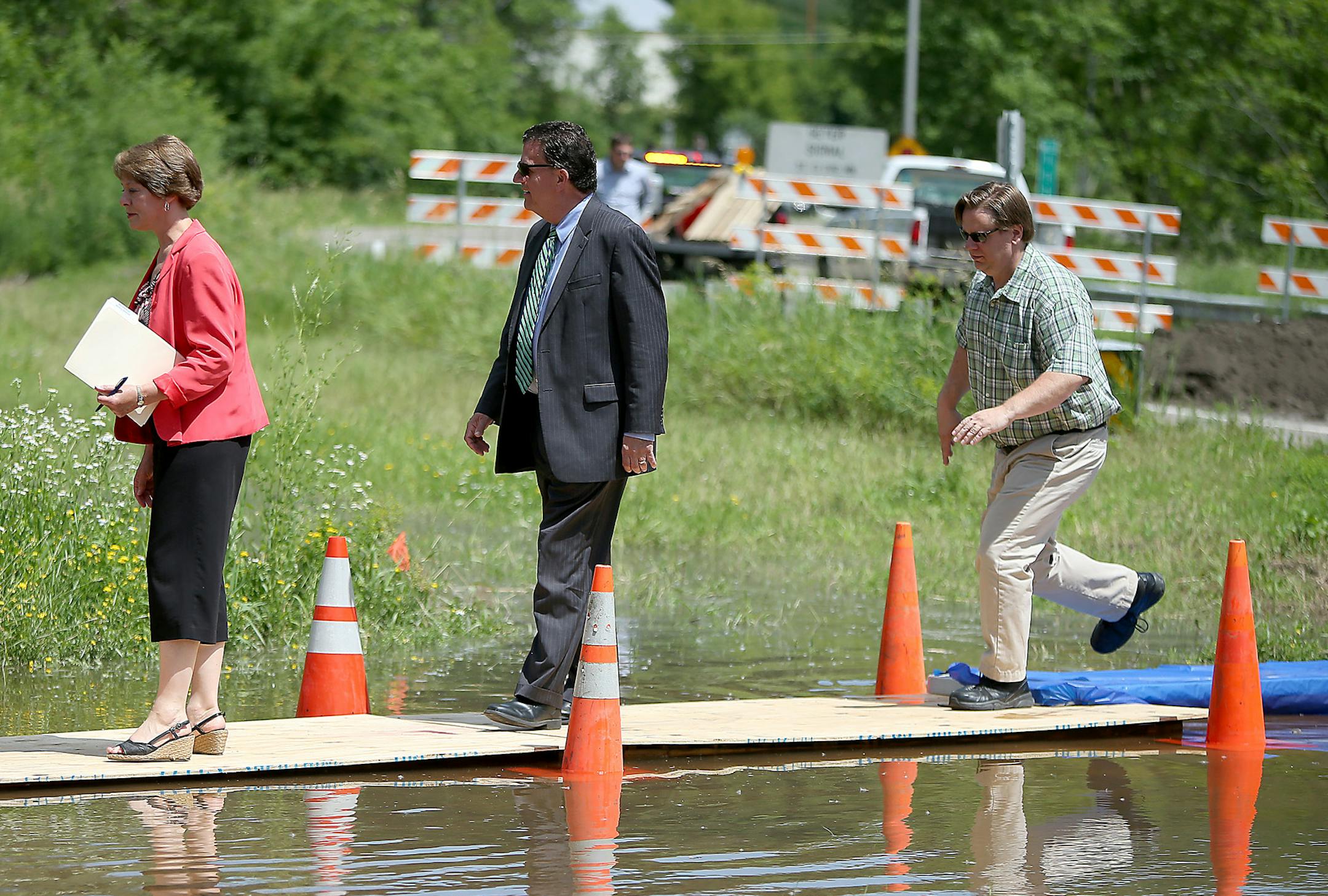 In Chaska, those attending the groundbreaking of a $50 million flood mitigation project had to use a makeshift plywood bridge to reach the event.