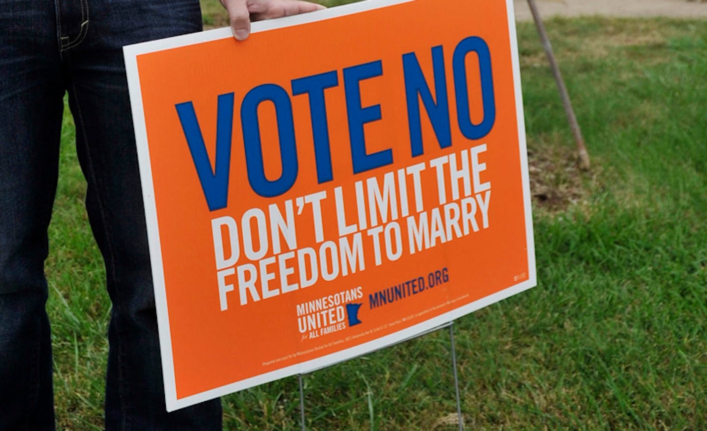 In this photo taken Friday, Sept. 21, 2012, Alexander Zachary stands by one of his Vote No signs at his Minneapolis home. Zachary is a gay man who takes issue with TV commercials against the gay marriage ban that feature straight people talking about the issue. Voters in Minnesota will decide the Gay Marriage Amendment in the November general election. (AP Photo/Jim Mone)