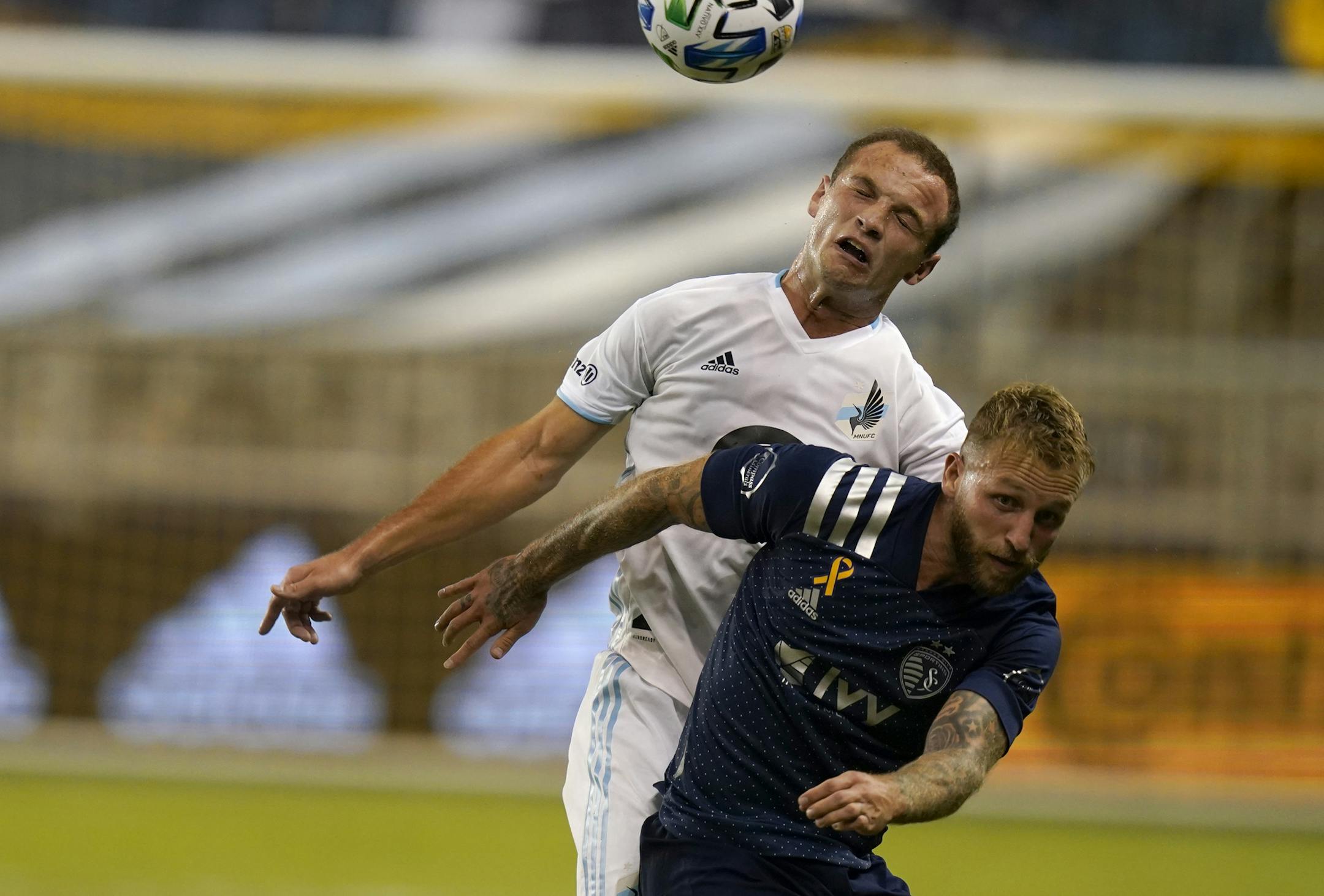Minnesota United defender Chase Gasper, back, heads the ball over Sporting Kansas City forward Johnny Russell during the second half of an MLS soccer match in Kansas City, Kan., Sunday, Sept. 13, 2020. Minnesota United defeated Sporting Kansas City 2-1. (AP Photo/Orlin Wagner) ORG XMIT: KSOW105