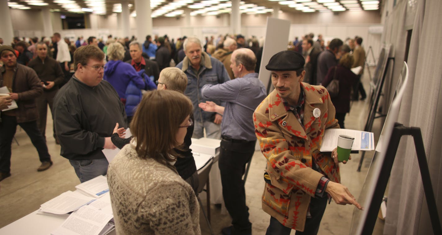 About 1500 people jammed a meeting room at the Duluth Entertainment and Convention Center Thursday night, January 16, 2013 for the first public hearing about a controversial open pit mine near Babbitt that has been proposed by PolyMet Mining Corp. of Canada. Mike Dahl, a member of the White Earth Band of Chippewa, asked questions about water quality of Melinda Todorov, who was working at that information table. He said he came because he is worried about how more mining will affect wild rice and