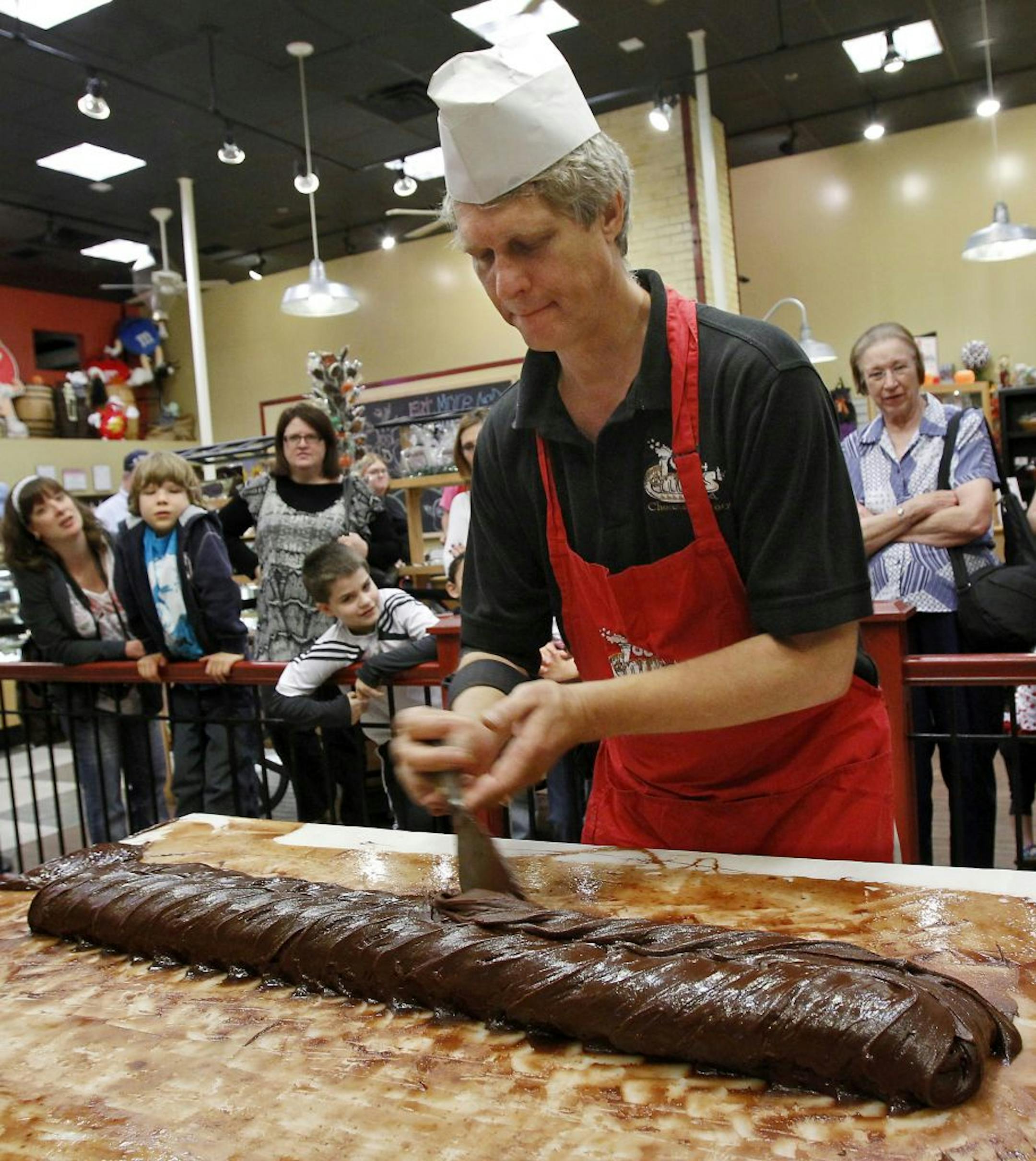 Retailers are offering entertainment to draw customers in the door. Cliff Smith, left, a fudge maker at Chip's Chocolate Factory at Crown Center in Kansas City, Missouri, demonstrates how the treat is made to an audience of potential customers.