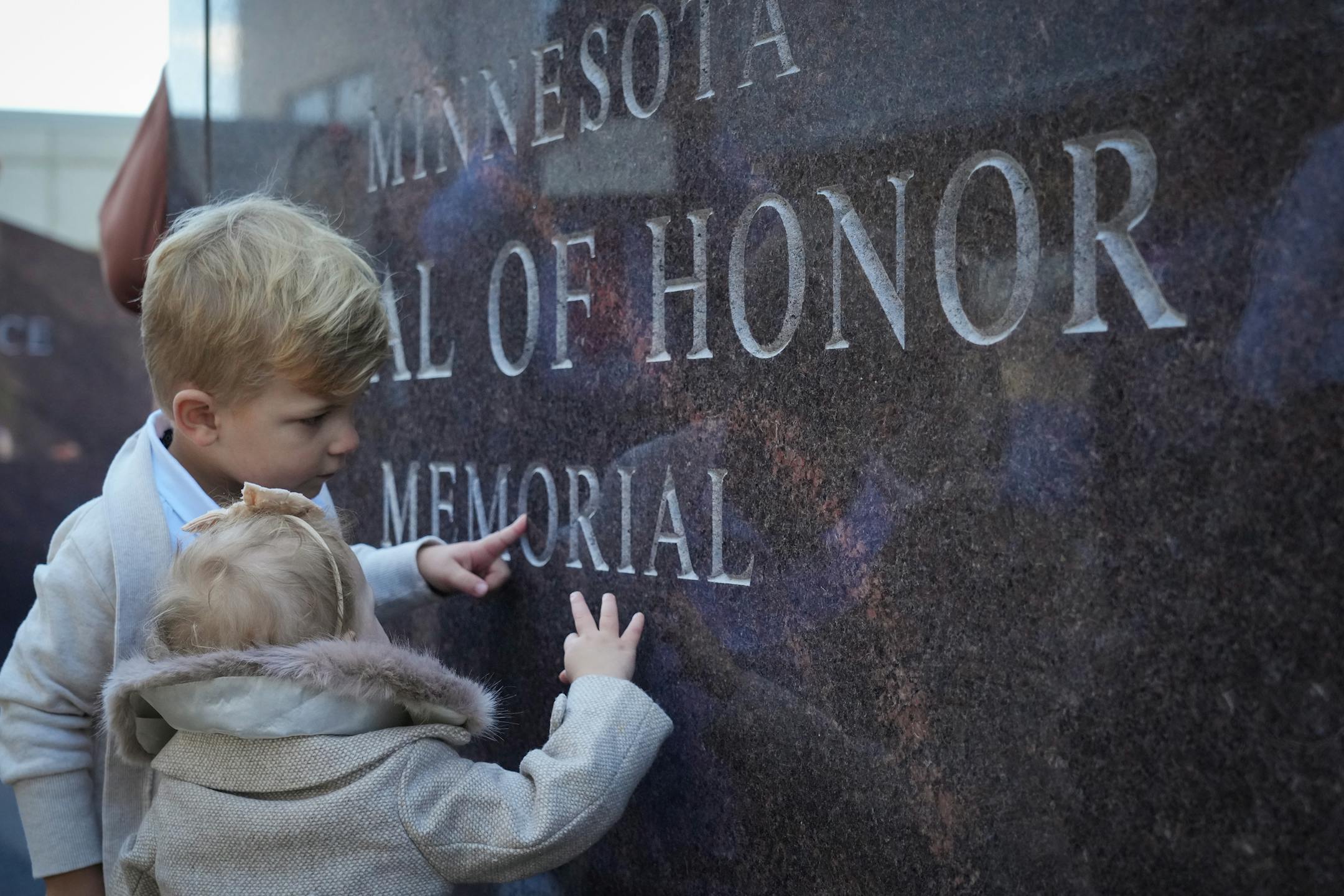 Elias, 3, and Elsie King, 15 months, from Maple Grove touch the engraving on the Minnesota Medal of Honor Memorial.