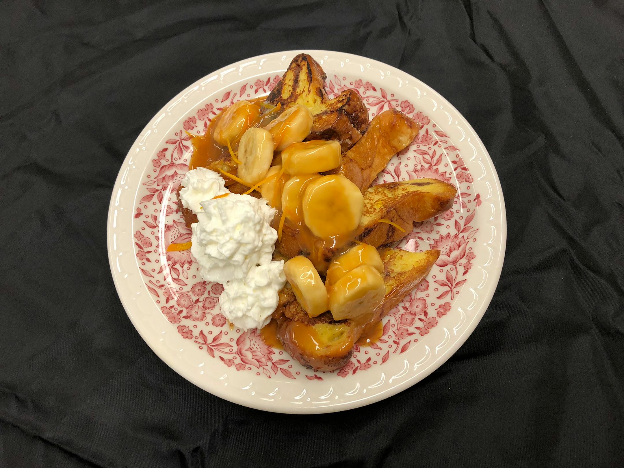 Bananas Foster French Toast: Cinnamon swirl French toast topped with slices of fresh bananas in an orange-rum-flavored caramel sauce and finished with a dollop of whipped cream. At Hamline Church Dining Hall, located on the north side of Dan Patch Avenue between Underwood & Cooper streets.