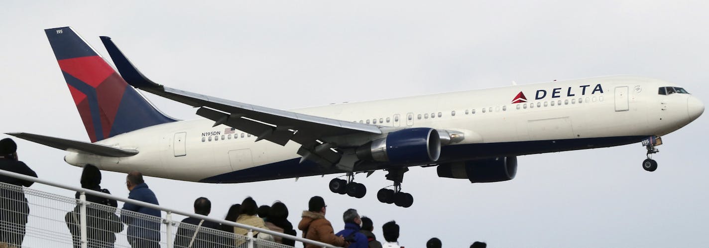 FILE - In this March 14, 2015 file photo, people watch a landing Delta Air Lines jet approach the Narita International Airport from a popular viewing spot at Sakuranoyama Park in Narita, east of Tokyo. Delta Air Lines reports quarterly financial results on Wednesday, April 15, 2015. (AP Photo/Koji Sasahara, File)