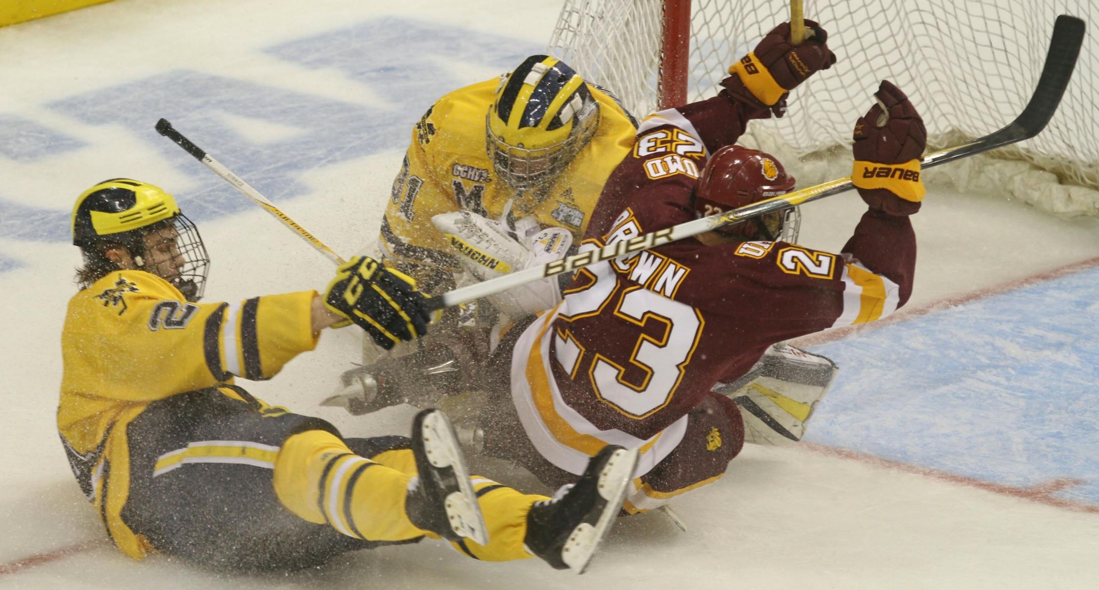 NCAA Frozen Four Finals, Minnesota Duluth vs Michigan. (left to right) Michigan's Jon Merrill pulled down UMD's J.T. Brown for a penality as Brown crashed the net.
