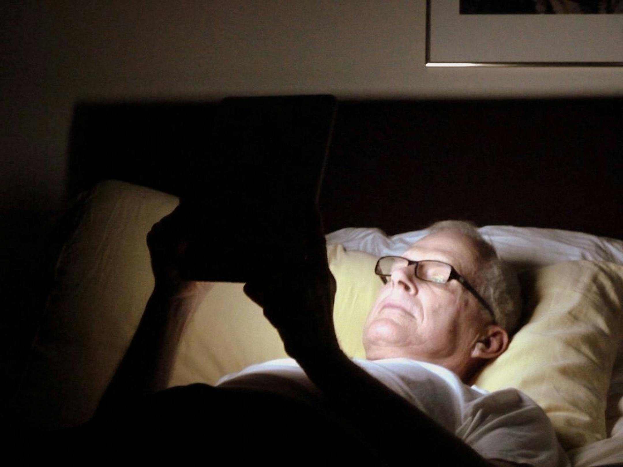 F. DelventhalMan reads iPad in bed