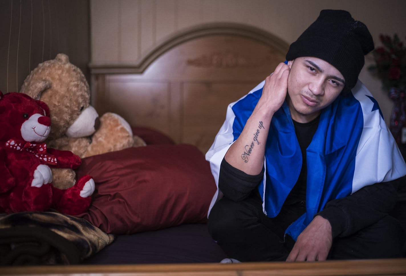 Elder Leiva, draped in the flag of Honduras in 2017 in Minnesota, three years after escaped his birth country because of the dangers posed by gangs. He had "Never Give Up" tattooed on his arm.