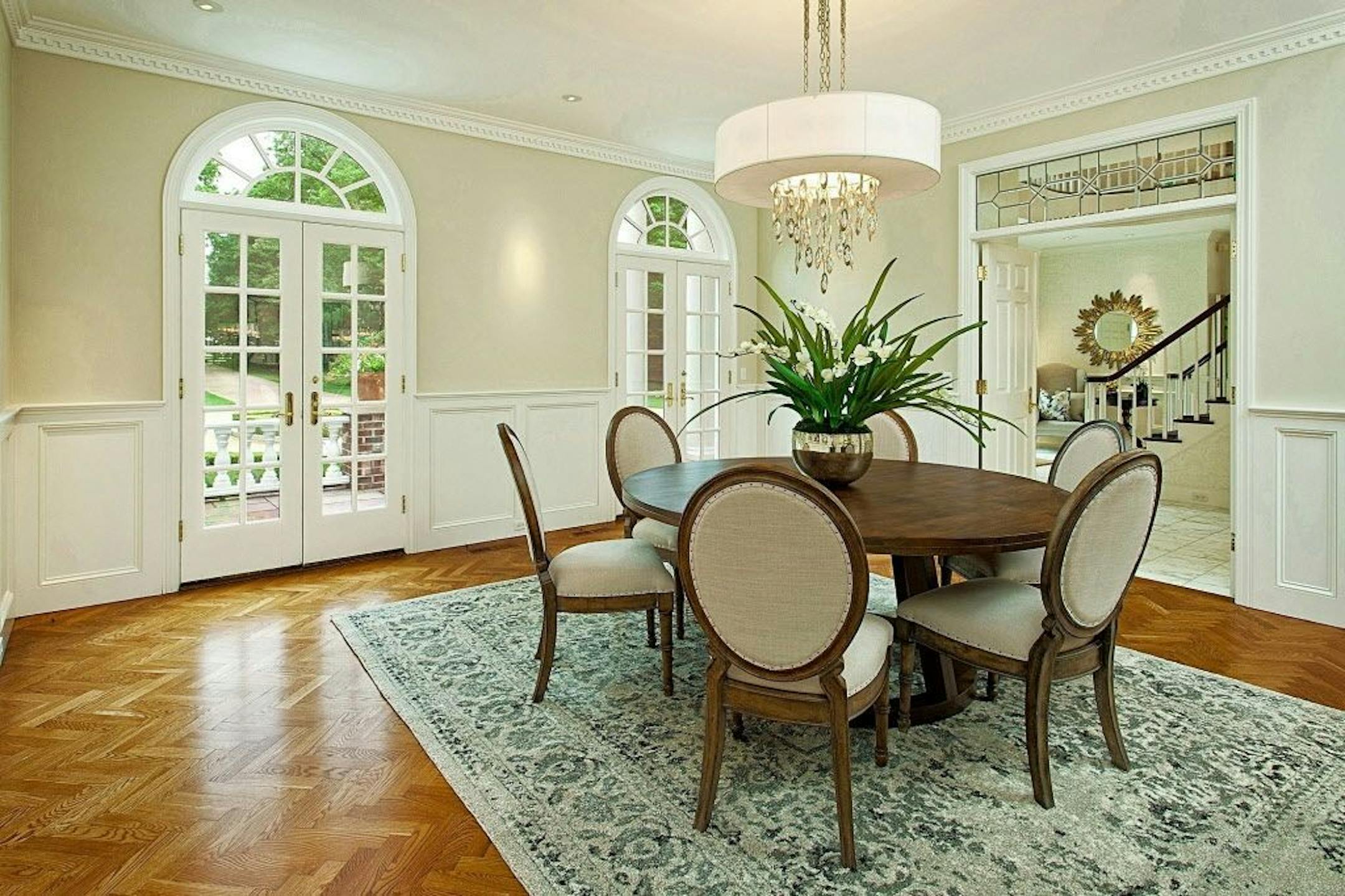 Dining room character includes enameled wainscoting, crown molding and Palladian French doors.
