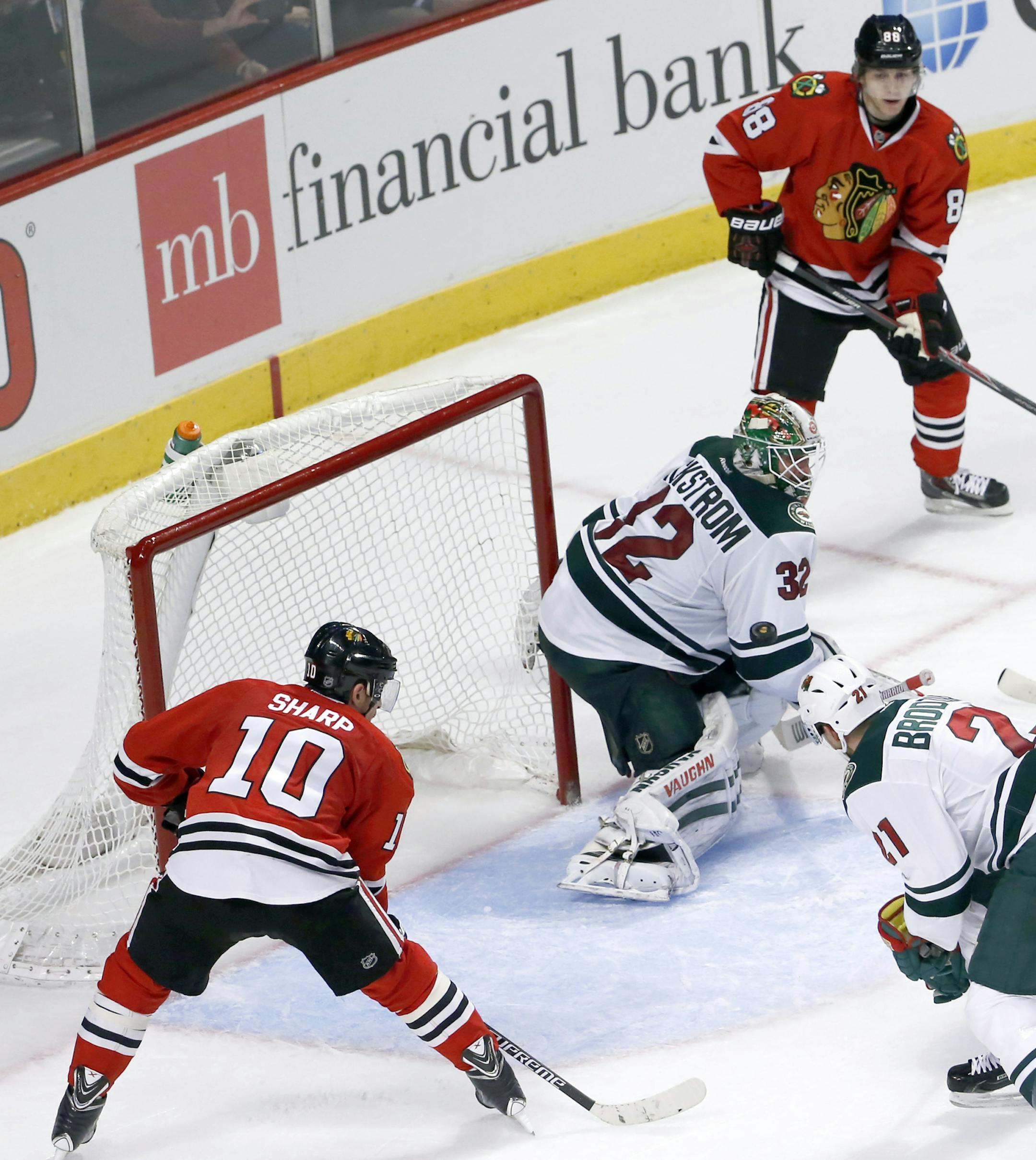 Chicago Blackhawks right wing Patrick Kane (88) watches his shot on Minnesota Wild goalie Niklas Backstrom go around Backstrom and score as Patrick Sharp (10) and Kyle Brodziak watch, during the third period of an NHL hockey game Tuesday, Dec. 16, 2014, in Chicago. The Blackhawks won 5-3. (AP Photo/Charles Rex Arbogast)