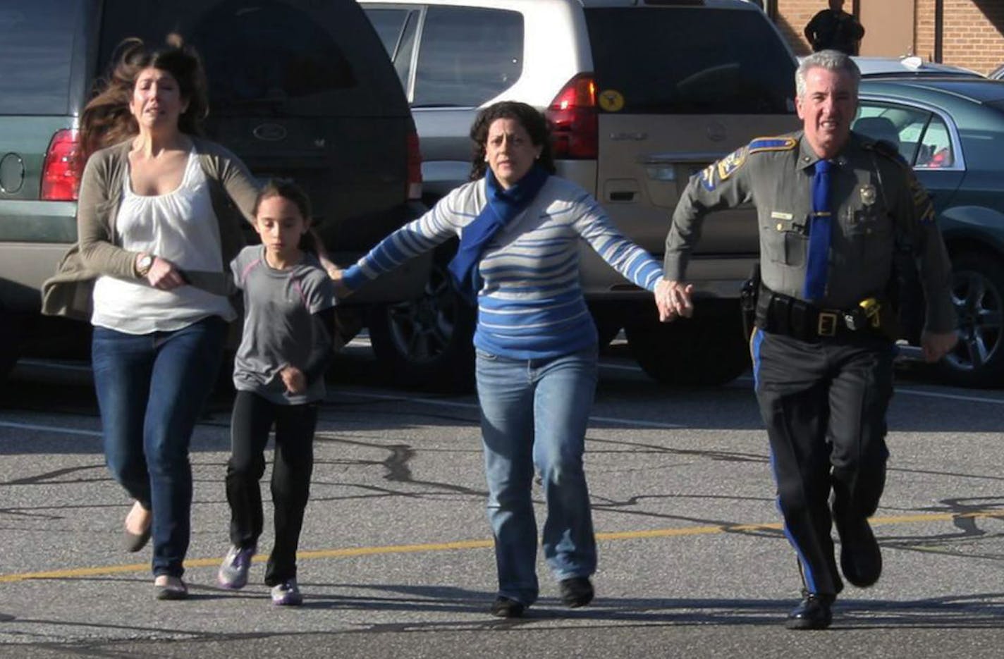 A police officer leads two women and a child from Sandy Hook Elementary School in Newtown, Conn., where a gunman opened fire, killing 26 people, including 20 children on Dec. 14, 2012.