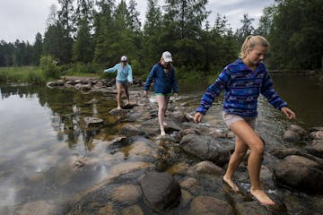 Emma Daniels, right, Abby MacFarlane and Marie Preston, back, walked across the rocks at the headwaters of the Mississippi at Lake Itasca in mid June.