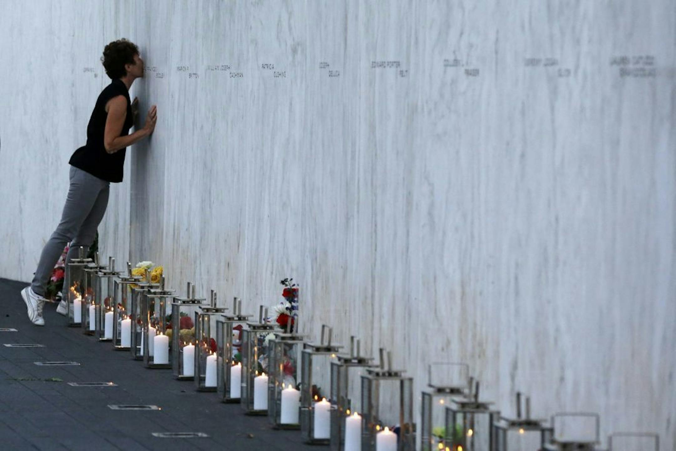 A visitor kisses an name on the wall containing the 40 names of the crew and passengers of Flight 93 at the Flight 93 National Memorial during a candlelight remembrance on Tuesday, Sept. 10, 2013.