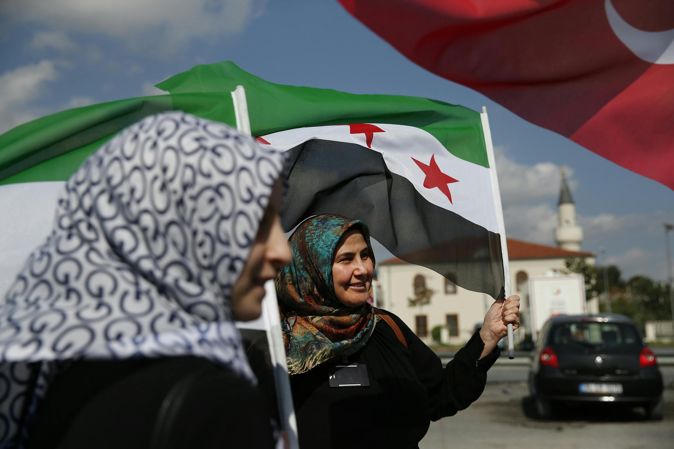 Members of a Turkish pro-government aid group, carrying Syrian and Turkish flags, wait for the departure of trucks carrying humanitarian aid destined for Idlib, Syria, in Istanbul, Monday, Sept. 10, 2018. The convoy of 20 vehicles will attempt to reach Syria to deliver basic needs. (AP Photo/Lefteris Pitarakis)