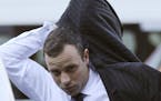 Oscar Pistorius puts on his jacket as he arrives at the high court in Pretoria, South Africa, Friday, April 11, 2014.