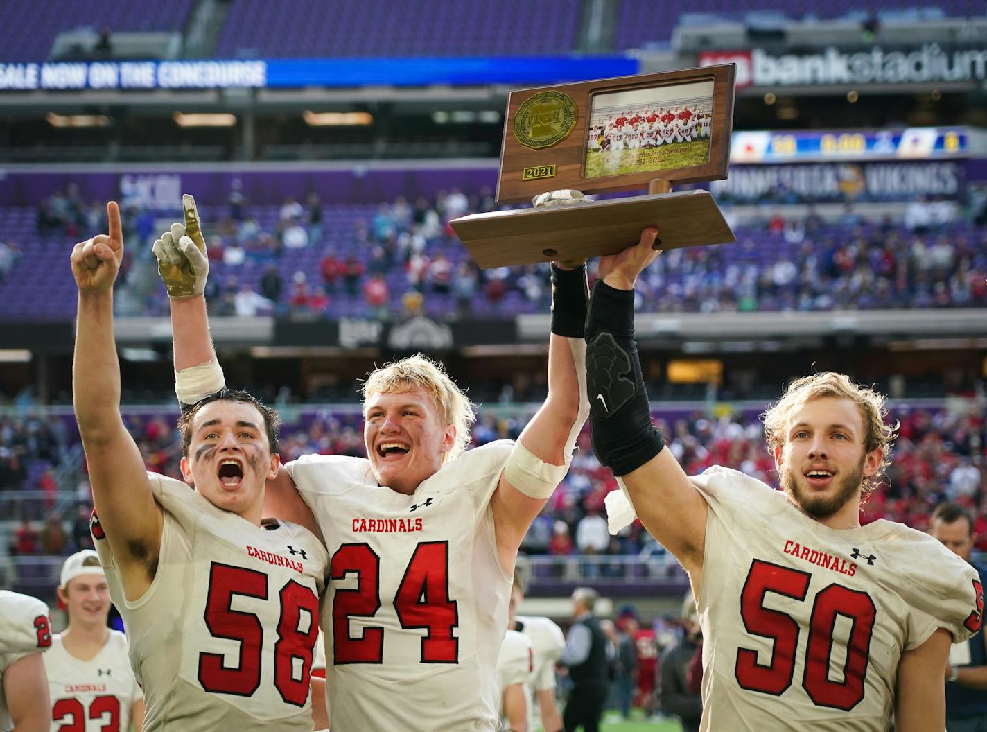 After defeating Fertile-Beltrami 58-8, LeRoy-Ostrander seniors Hayden Sass (58), Gavin Sweeney (24) and Tanner Olson (50) hold up the trophy for fans after the 9-man football championship at the US Bank Stadium in Minneapolis, Minn., on Saturday, Nov. 27, 2021. ] SHARI L. GROSS • shari.gross@startribune.com