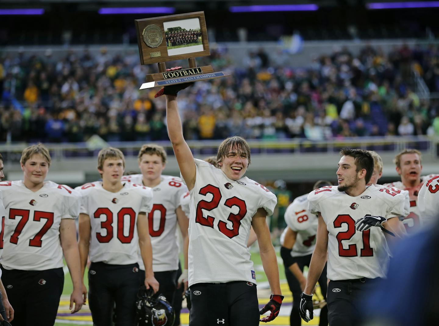 Adin Solum carried the championship trophy for Spring Grove after defeating Nevis 32-0 for the 9-Man championship.