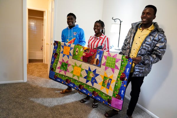 Refugees from Congo Sadock Ekyochi, from left, his wife Riziki Kashindi and her brother Kaaskile Kashindi pose for a photo inside their new apartment,