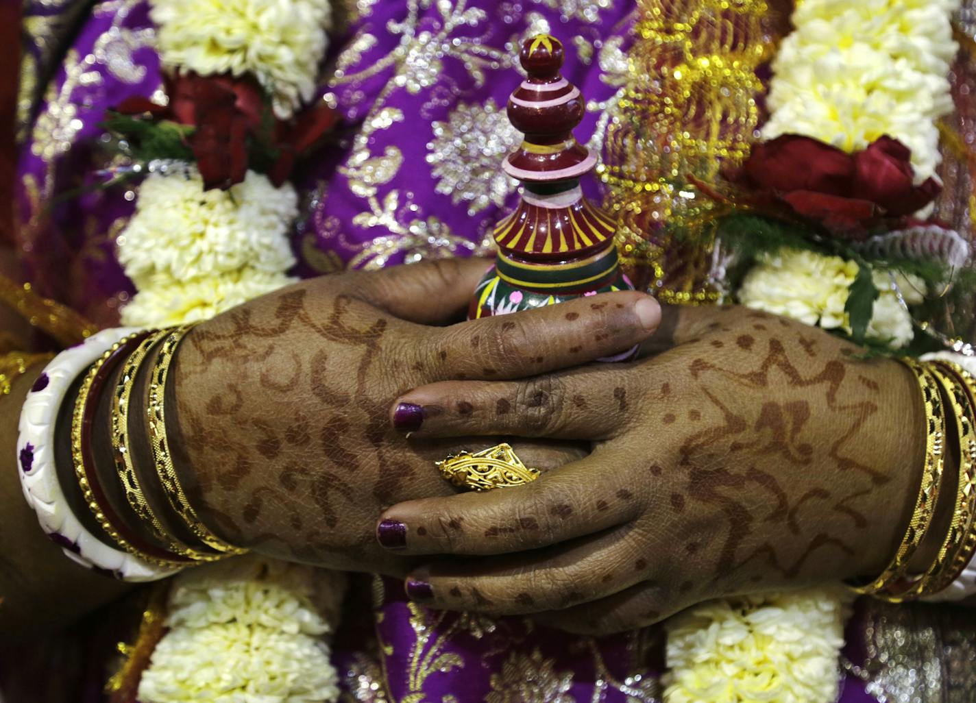 A Hindu bride carries a sacred pot of vermillion prior to performing rituals during a community mass wedding ceremony on Valentine Day in Kolkata, India, Wednesday, Feb. 14, 2018. One hundred and sixty couples belonging to various communities got married at this event organized by a non-government social organization. (AP Photo/Bikas Das)