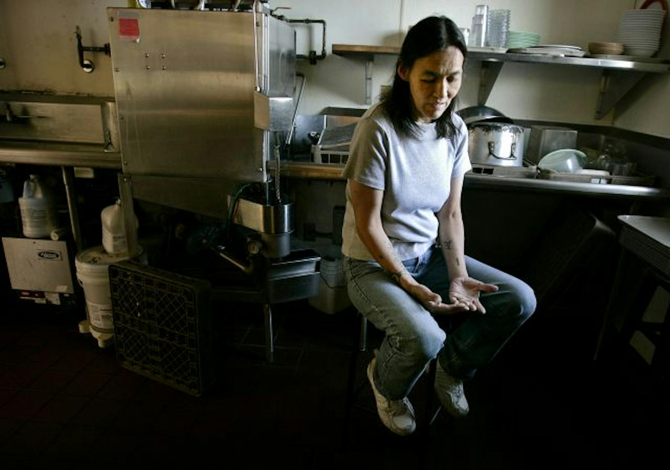 Denise Ellis sits in the kitchen of Anishinabe Wakiagun, a "wet house" treatment facility for chronic alcoholics that permits them to continue drinking, where she lives.