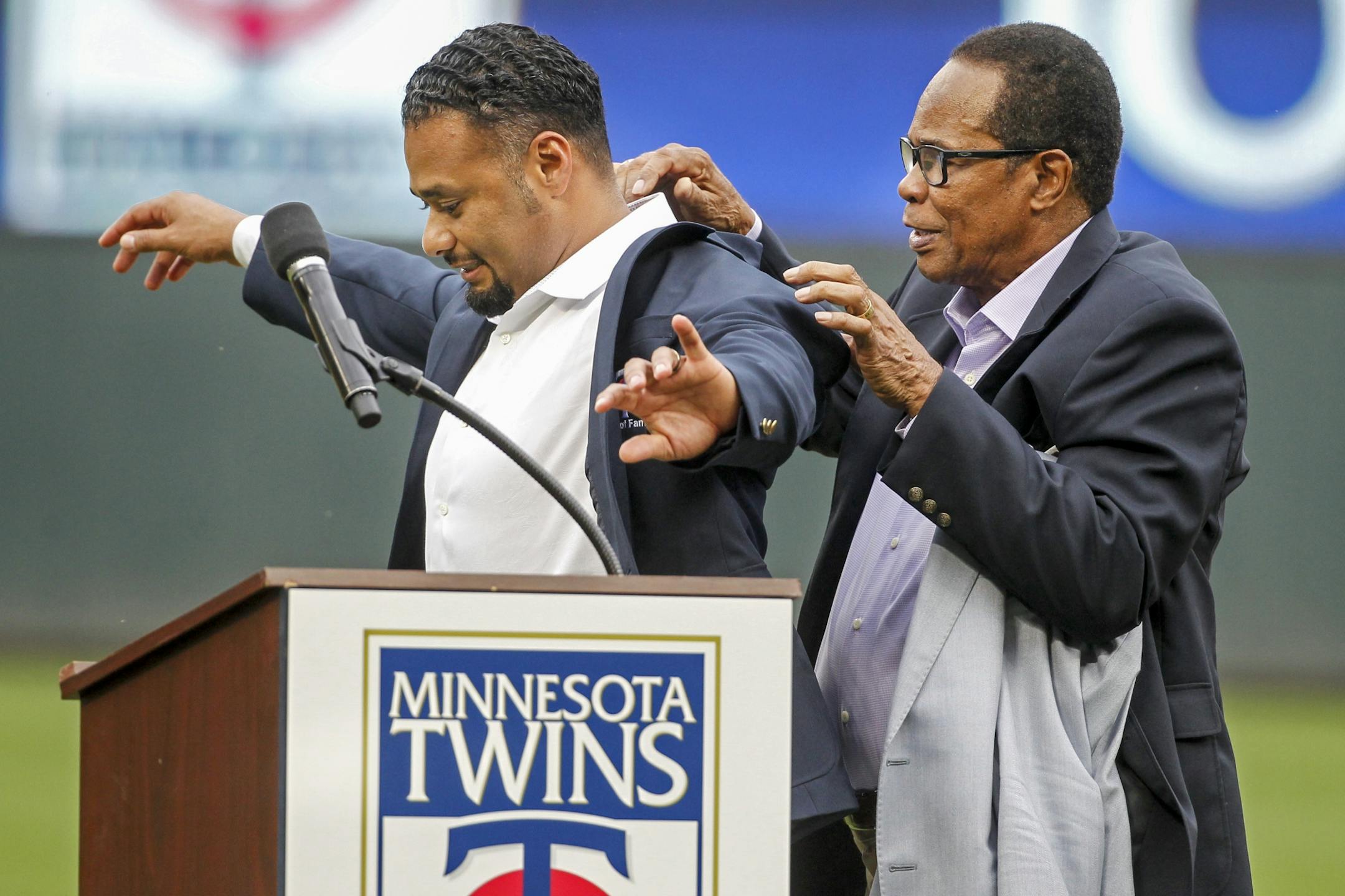 Hall of Fame player player Rod Carew, right, puts on a Minnesota Twins Hall of Fame jacket to former Twins pitcher Johan Santana at his induction ceremony before the baseball game with the Kansas City Royals on Saturday, Aug. 4, 2018, in Minneapolis.