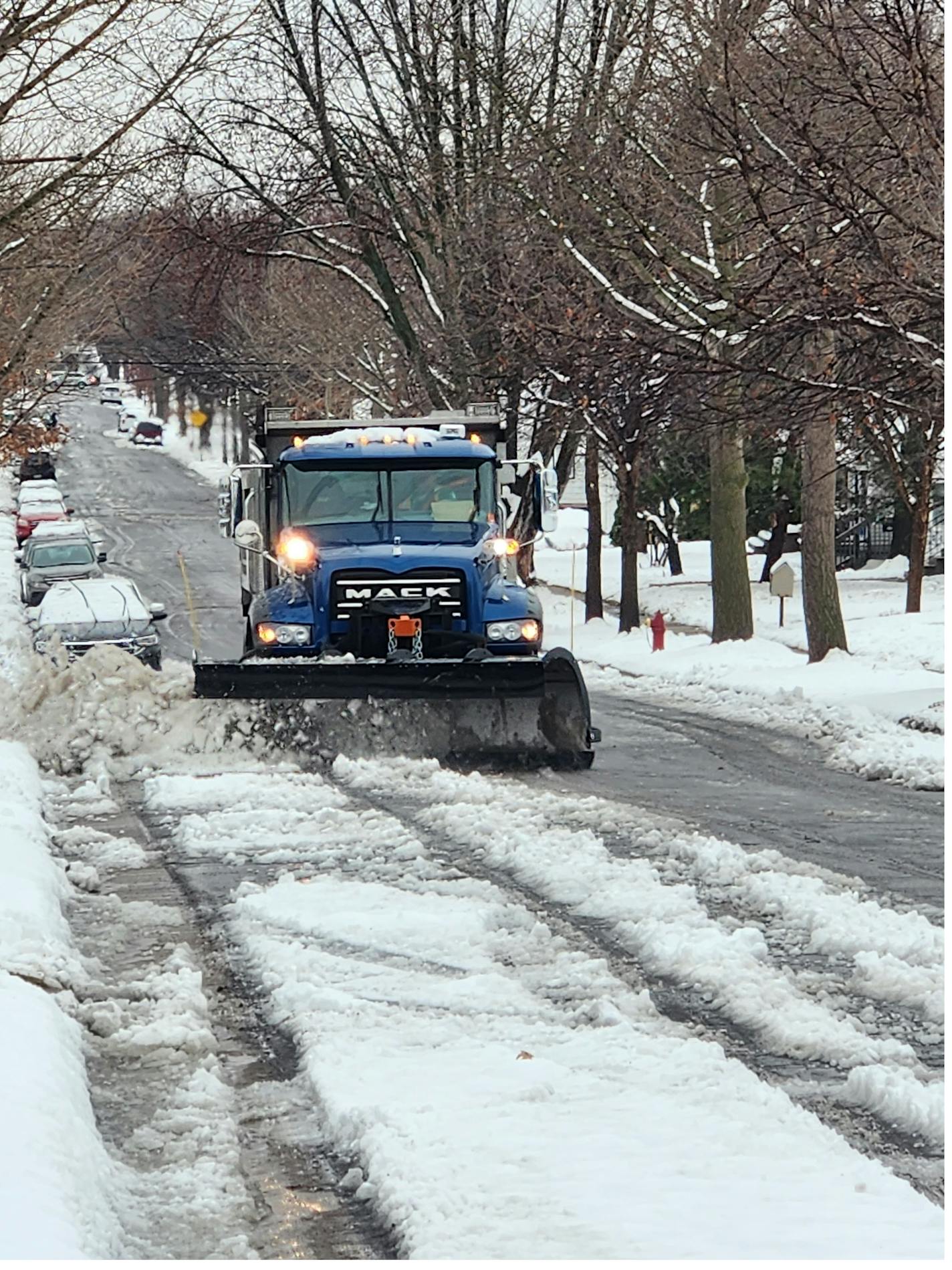 A City of St. Paul snowplow truck clears snow from a residential street.