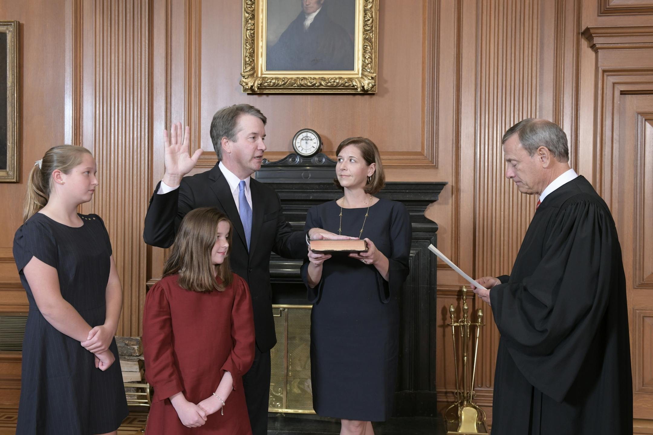 Chief Justice John Roberts, right, administers the Constitutional Oath to Judge Brett Kavanaugh in the Justices' Conference Room of the Supreme Court Building. Ashley Kavanaugh holds the Bible. In the foreground are their daughters, Margaret, left, and Liza.
