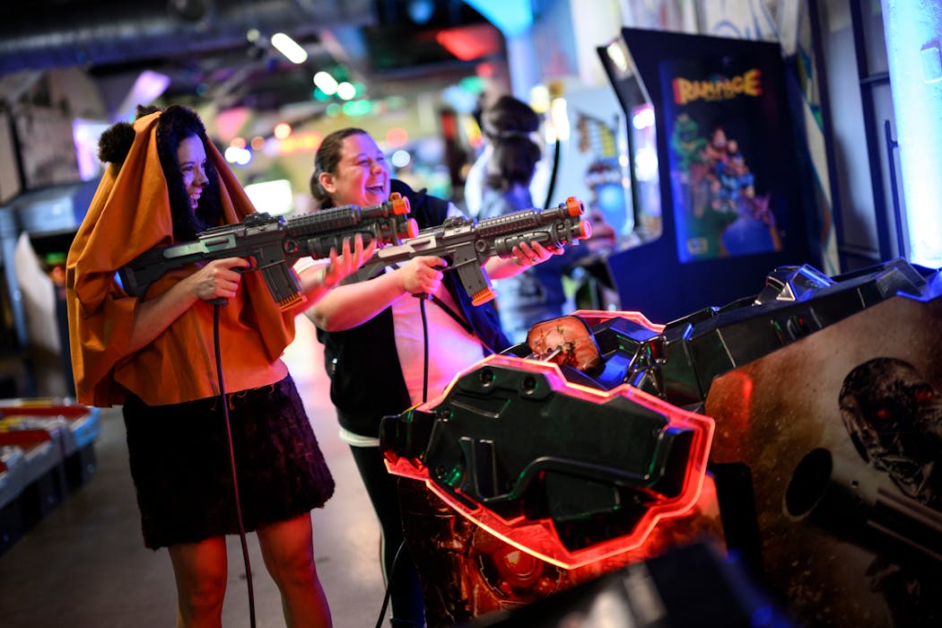 Jasmine Roop, left, dressed as Wicket the Ewok from Star Wars, plays a Terminator arcade game with her sister, Grace Davis, during a 