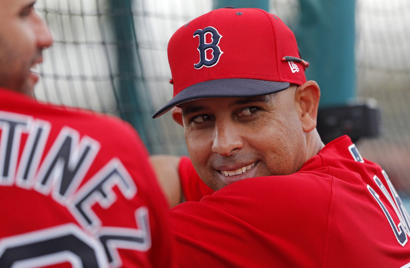 Boston Red Sox manager Alex Cora smiles from behind the batting cage during their first full squad workout at their spring training baseball facility in Ft. Myers, Fla., Monday, Feb. 18, 2019. (AP Photo/Gerald Herbert)