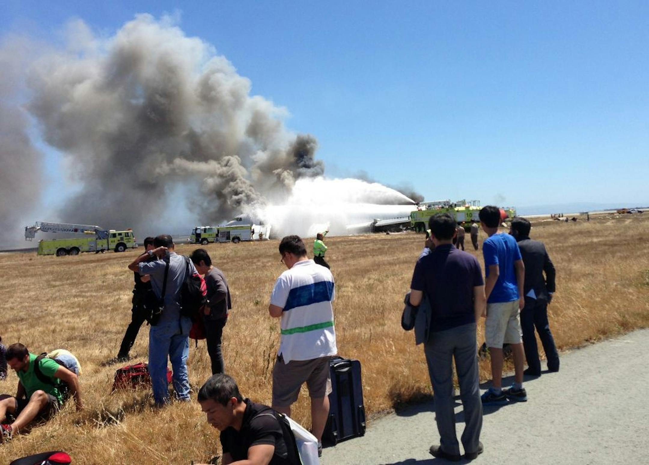 In this Saturday, July 6, 2013, photo provided by passenger Benjamin Levy, passengers from Asiana Airlines flight 214, many with their luggage, on the tarmac just moments after the plane crashed at the San Francisco International Airport.