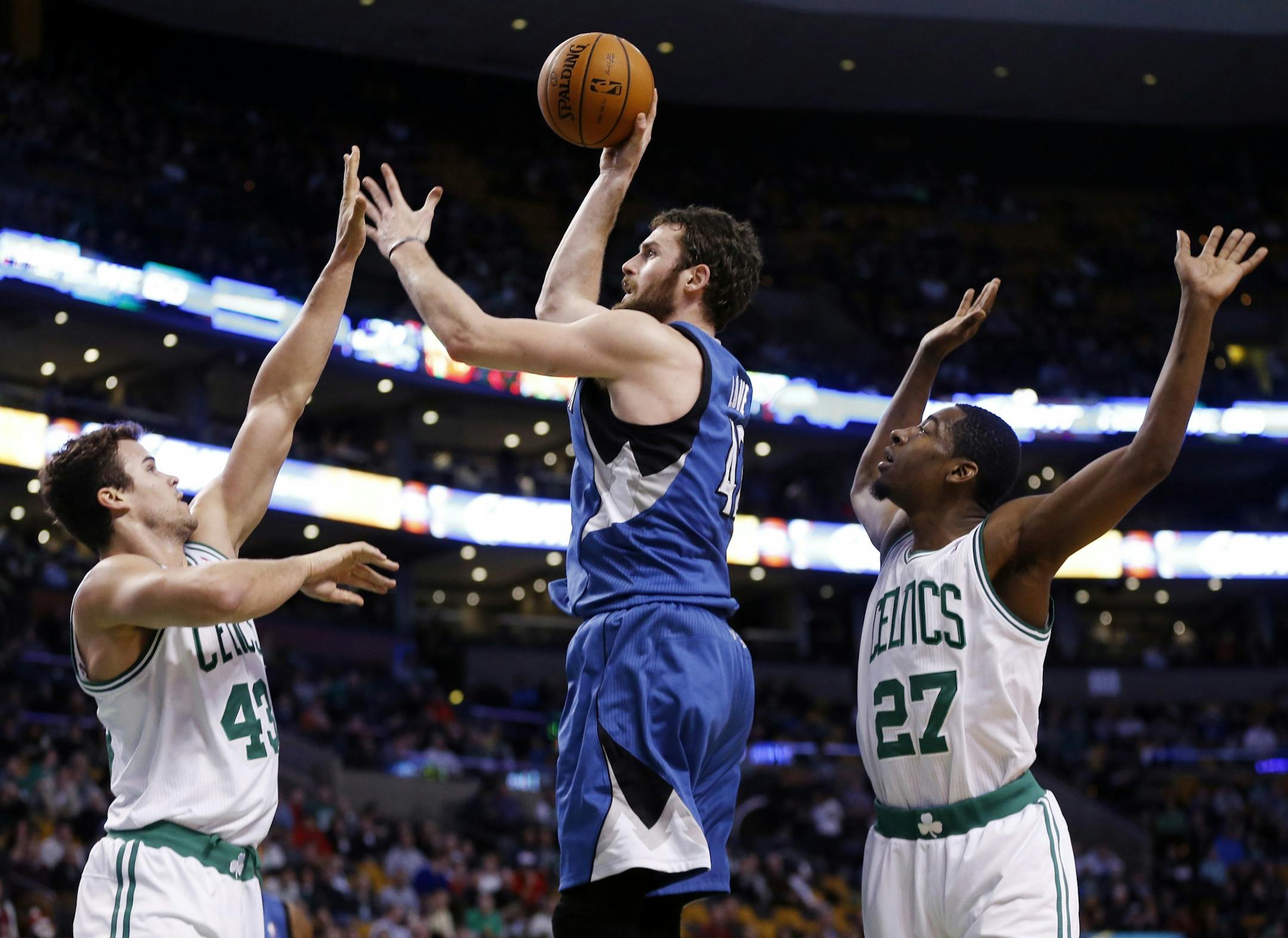 Minnesota Timberwolves' Kevin Love, center, shoots between Boston Celtics' Kris Humphries (43) and Jordan Crawford (27) in the first quarter of an NBA basketball game in Boston, Monday, Dec. 16, 2013.