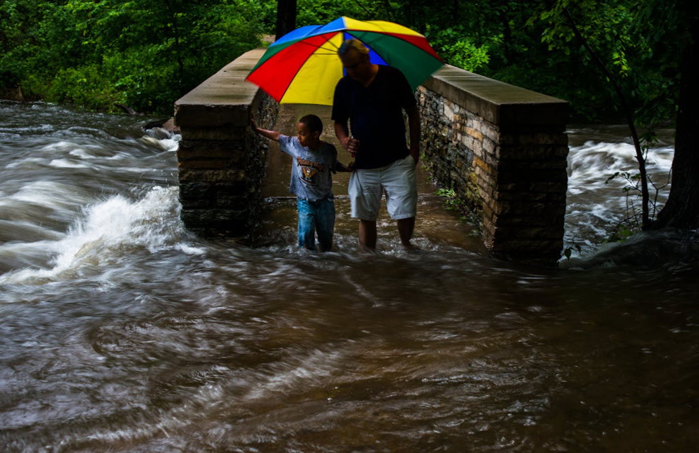 File photo of flooding along Minnehaha Creek in Minneapolis on in June 2014. Craig Susag and his grandson Nethaniel crossed a flooded bridge over the creek in Minnehaha Park.