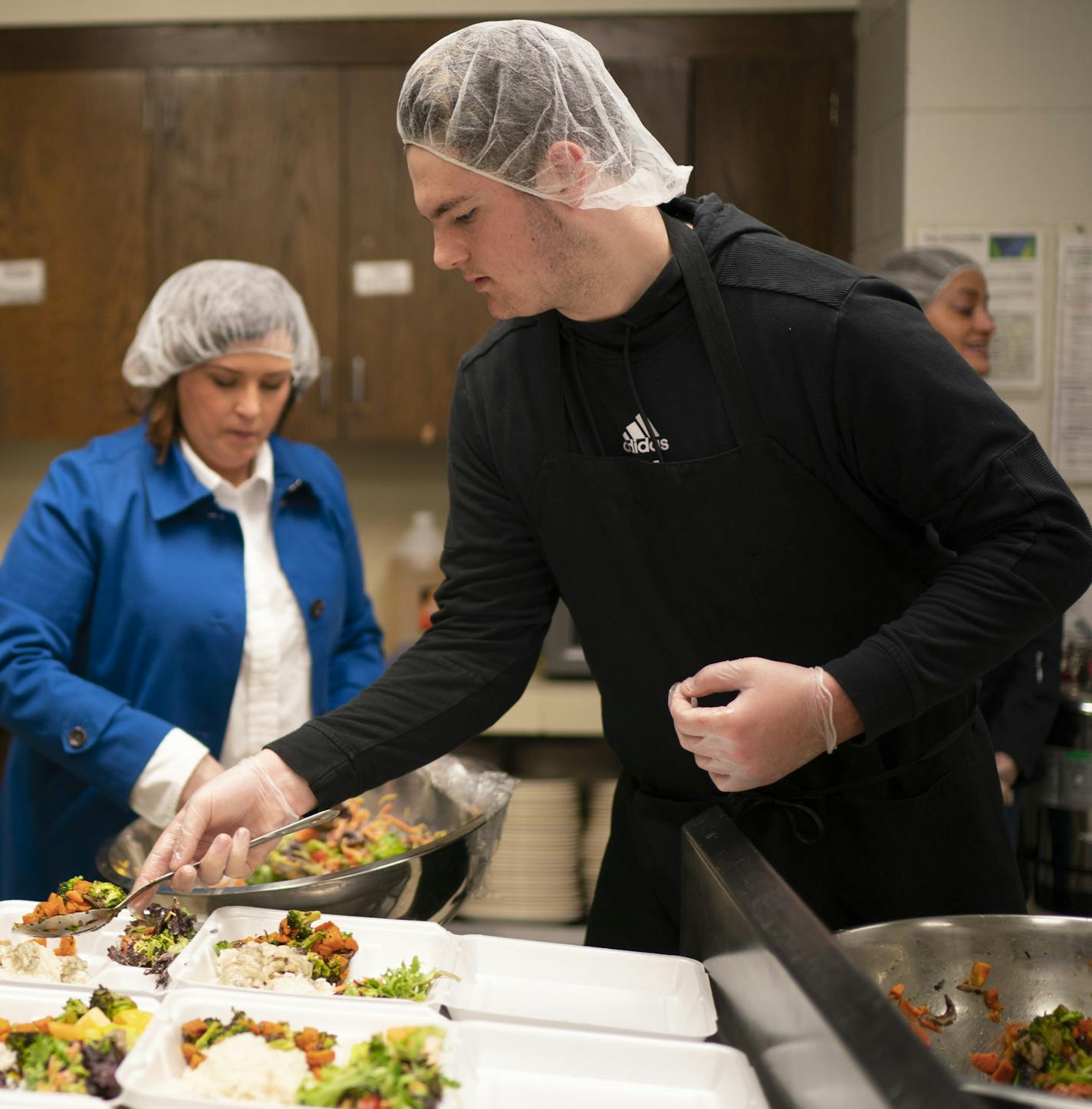 Liz Mullen, Chowgirls Killer Catering executive chef, left, Allison O'Toole, Second Harvest Heartland CEO, and volunteer Ty Larsen assembled meals in the kitchen of Hope Presbyterian Church Monday evening. ] JEFF WHEELER • Jeff.Wheeler@startribune.com Minnesota Central Kitchen, a coordinated effort of Second Harvest Heartland with Loaves and Fishes and Chowgirls Killer Catering produced meals at Hope Presbyterian Church Monday, evening March 30, 2020 in Richfield.