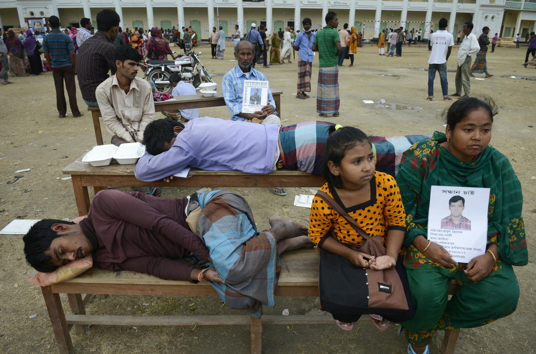 Relatives of missing garment workers wait for news of missing loved ones, as nearby workers and army personnel, not pictured, use heavy machinery as they work to clear the site and recover bodies of victims from the rubble of a garment factory building collapse, Monday, May 6, 2013, in Savar near Dhaka, Bangladesh. The death toll from the collapse of a shoddily built garment-factory building on April 24, in Bangladesh, continued its horrifying climb, reaching at least 630 on Monday with little s