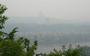 The Cathedral of St. Paul is seen through wildfire smoke and rainy conditions from across the Mississippi River in St. Paul on Tuesday morning. A stat