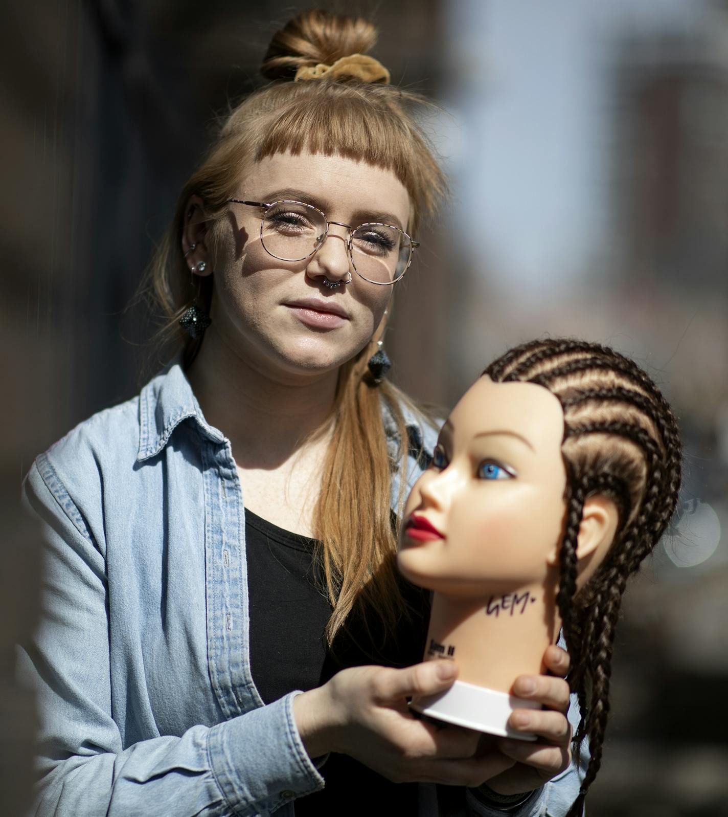 Gem Russell, a student at Aveda Institute, must practice hairstyling on a mannequin.