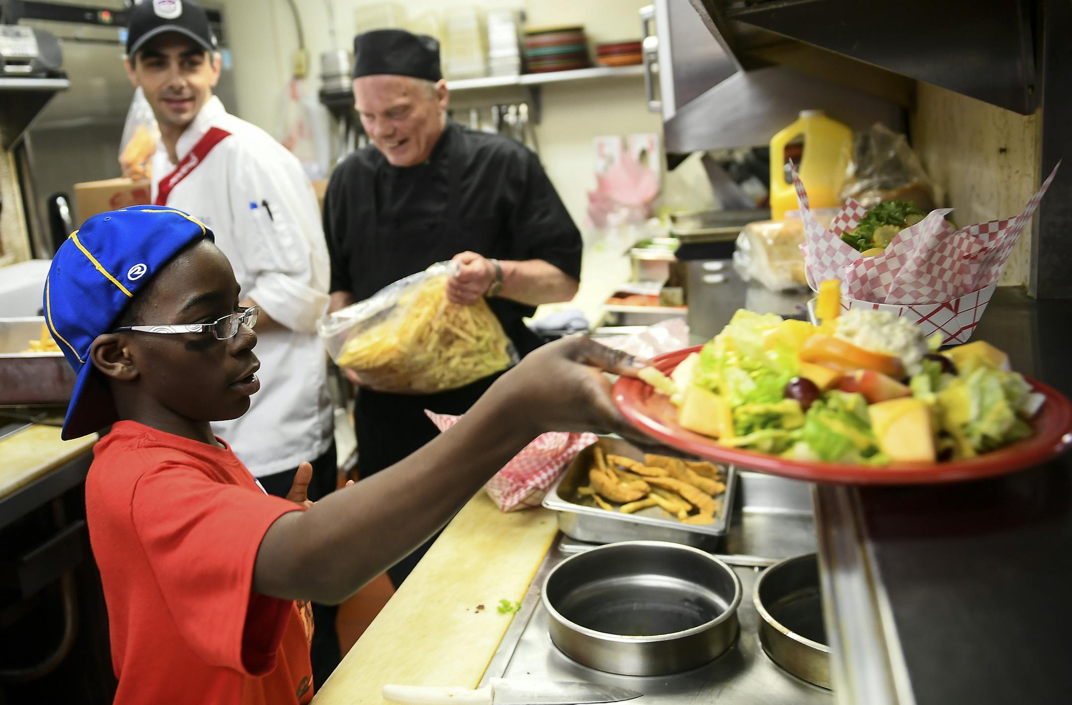 Edward Bartee, 12, handed a salad he made to a server Thursday at Peg's Countryside Cafe as part of the "Graft's Grill Goes Sporty" program. ] AARON LAVINSKY Ô aaron.lavinsky@startribune.com 12 students, with the Interfaith Outreach Neighborhood Program took over dinner restaurant operations at Peg's Countryside Cafe on Thursday, March 30, 2017 in Hamel, Minn. The program, "Graft's Grill Goes Sporty," is meant to teach students real-world, hands-on experiences in a workplace. ORG XMIT: MIN1