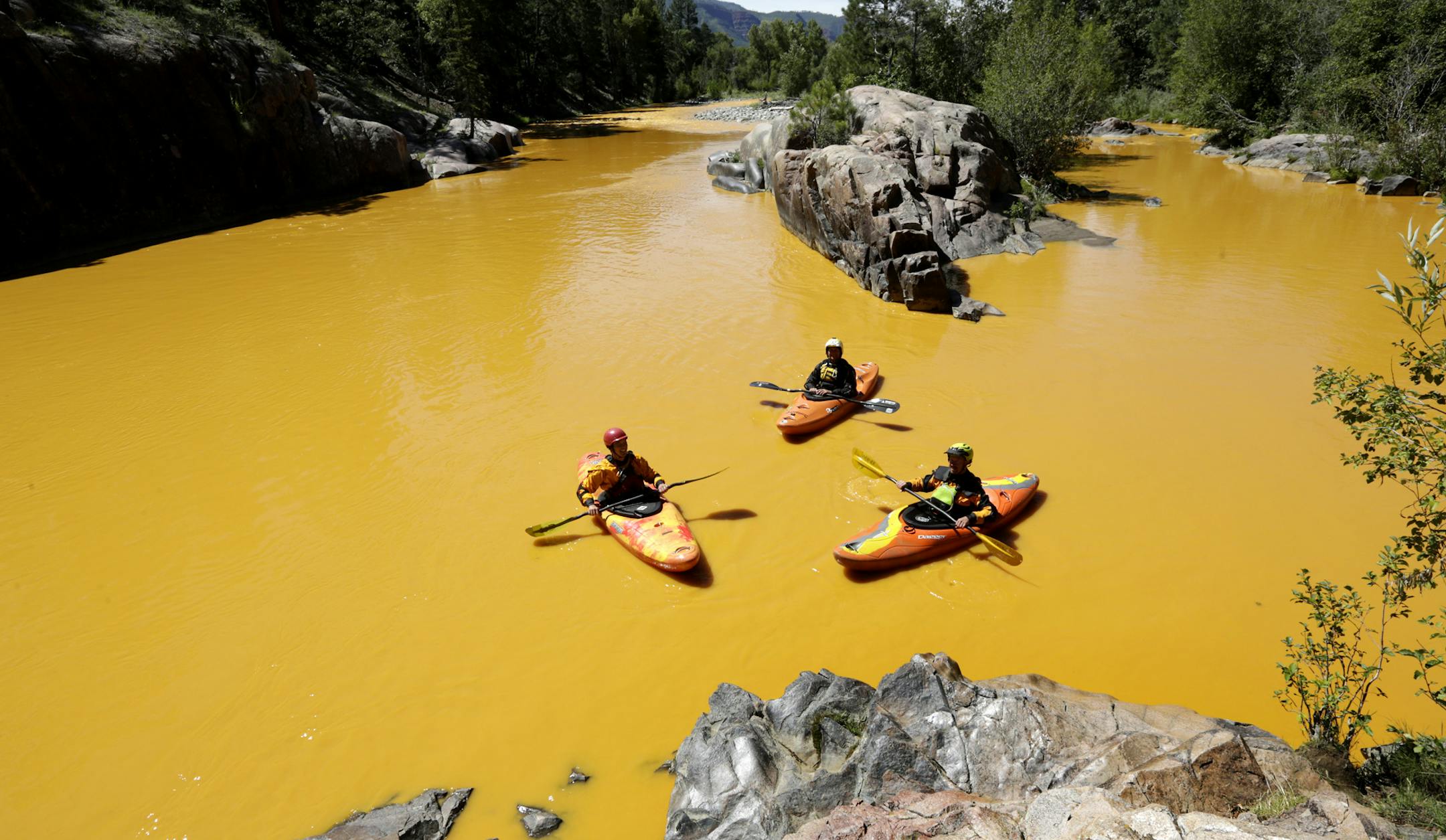 FILE - In this Thursday, Aug. 6, 2015 file photo, people kayak in the Animas River near Durango, Colo., in water colored yellow from a mine waste spill. A crew supervised by the U.S. Environmental Protection Agency has been blamed for causing the spill while attempting to clean up the area near the abandoned Gold King Mine. Tribal officials with the Navajo Nation declared an emergency on Monday, Aug. 10, as the massive plume of contaminated wastewater flowed down the San Juan River toward Lake P