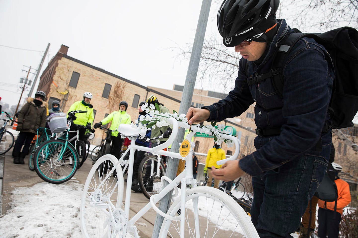 David Fernandez, far right, a friend and co-worker of Jose Hernandez Solano, puts a Brasa ornament on his ghost bike memorial.