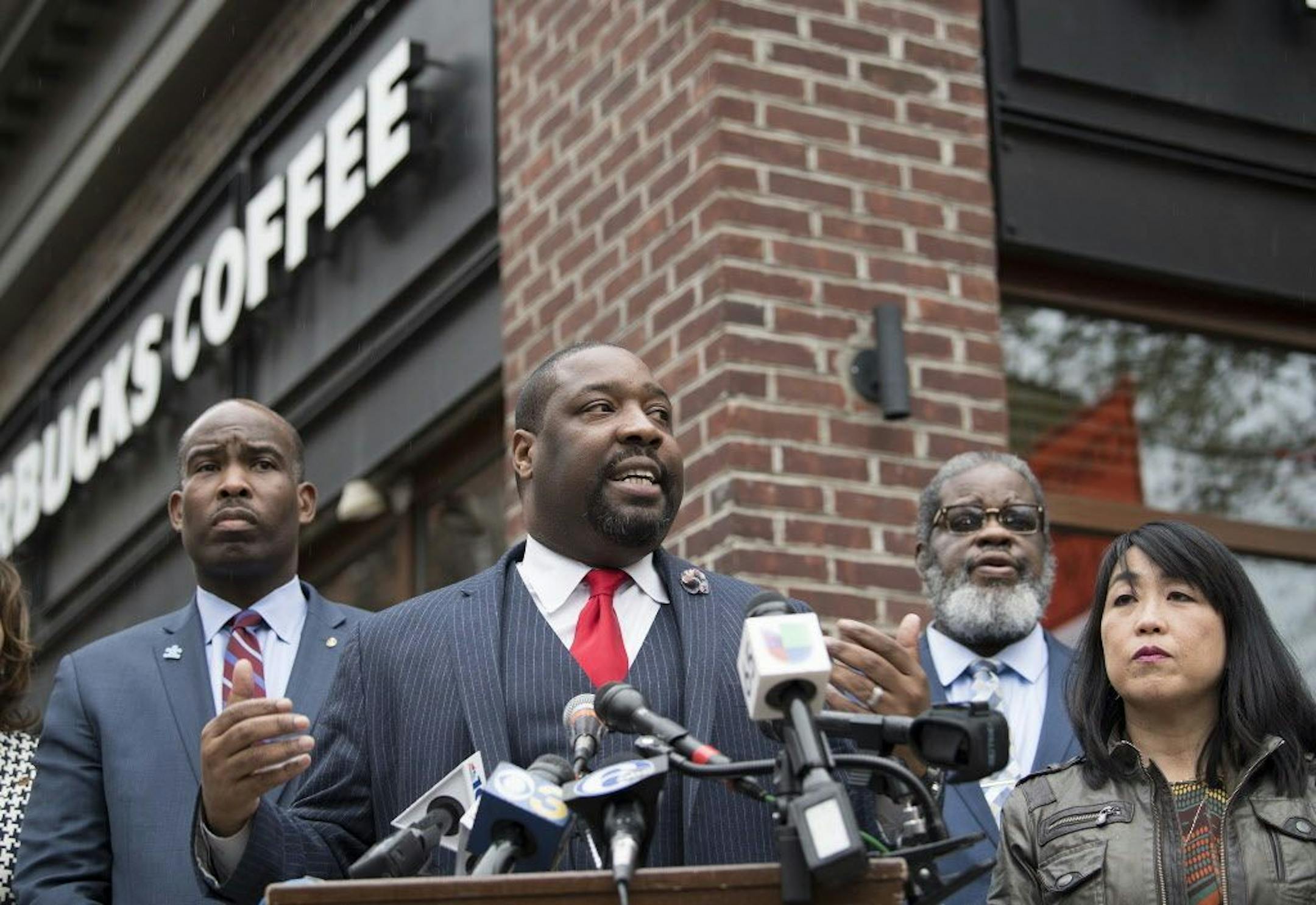 Philadelphia City Councilman, Kenyatta Johnson, center, flanked by two fellow members, speaks at the podium during a press conference outside the Starbucks on 18th & Spruce Streets in Philadelphia, Monday, April 16, 2018.