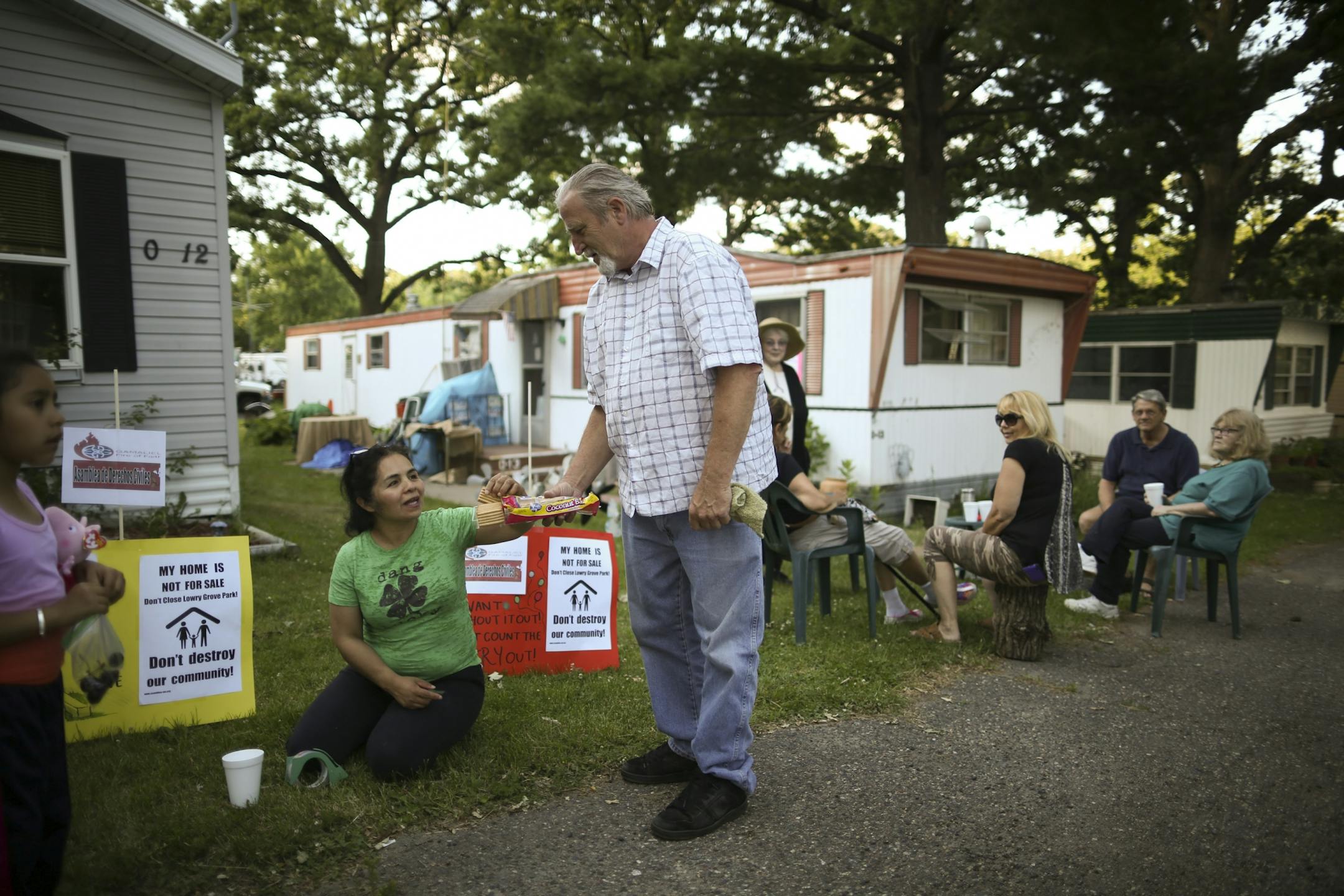 Bill McConnell offered Antonia Alvarez a cookie as residents of Lowry Grove mobile home park gathered informally Thursday evening. Alvarez led effort by tenants to buy the land their homes are on.