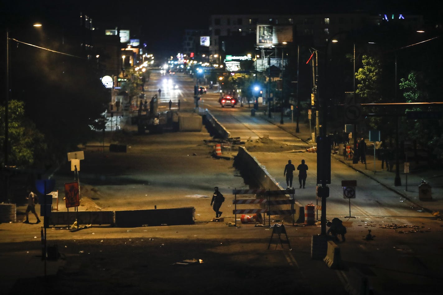 Few pedestrians walk down East Lake Street in an area recently cleared by police, Saturday, May 30, 2020, in Minneapolis. Protests continued following the death of George Floyd, who died after being restrained by Minneapolis police officers on Memorial Day. (AP Photo/John Minchillo)