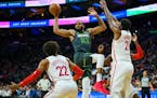 The Timberwolves' Karl-Anthony Towns, center, passes the ball while Philadelphia 76ers' Joel Embiid, right, defends the basket during the first half S