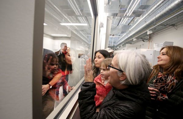 Julie Grossman of St. Paul holds her daughter Juniper Kirsch, 3, as they looked through a window into the extraction room for the opening of the new 1