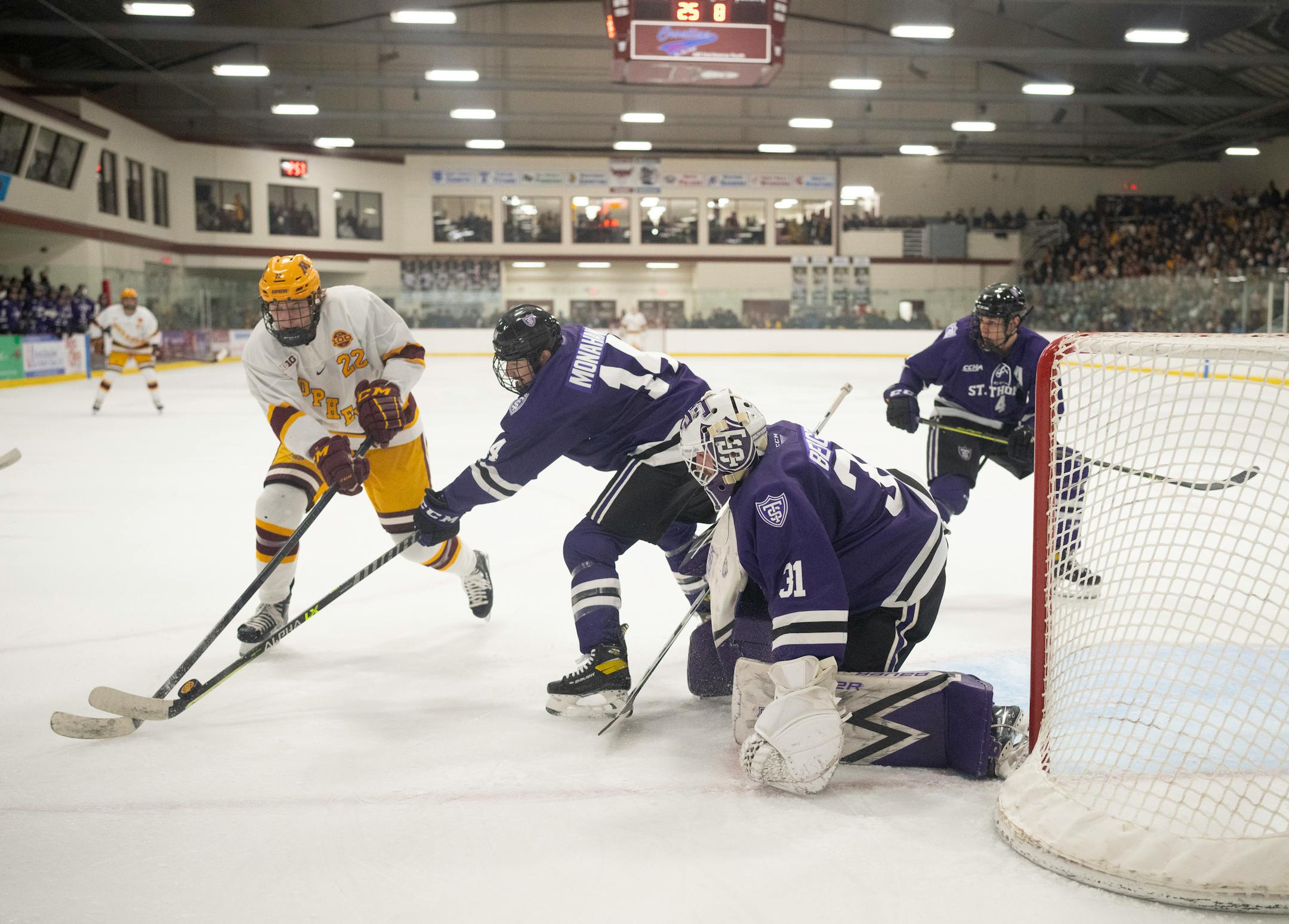 Gophers forward Bryce Brodzinski (22) and Tommies defenseman Shayne Monahan (14) tried to gain control of the puck in front of Tommies goaltender Jacob Berger (31) in the second period Sunday afternoon, Jan. 2, 2022 at Doug Woog Arena in South St. Paul.