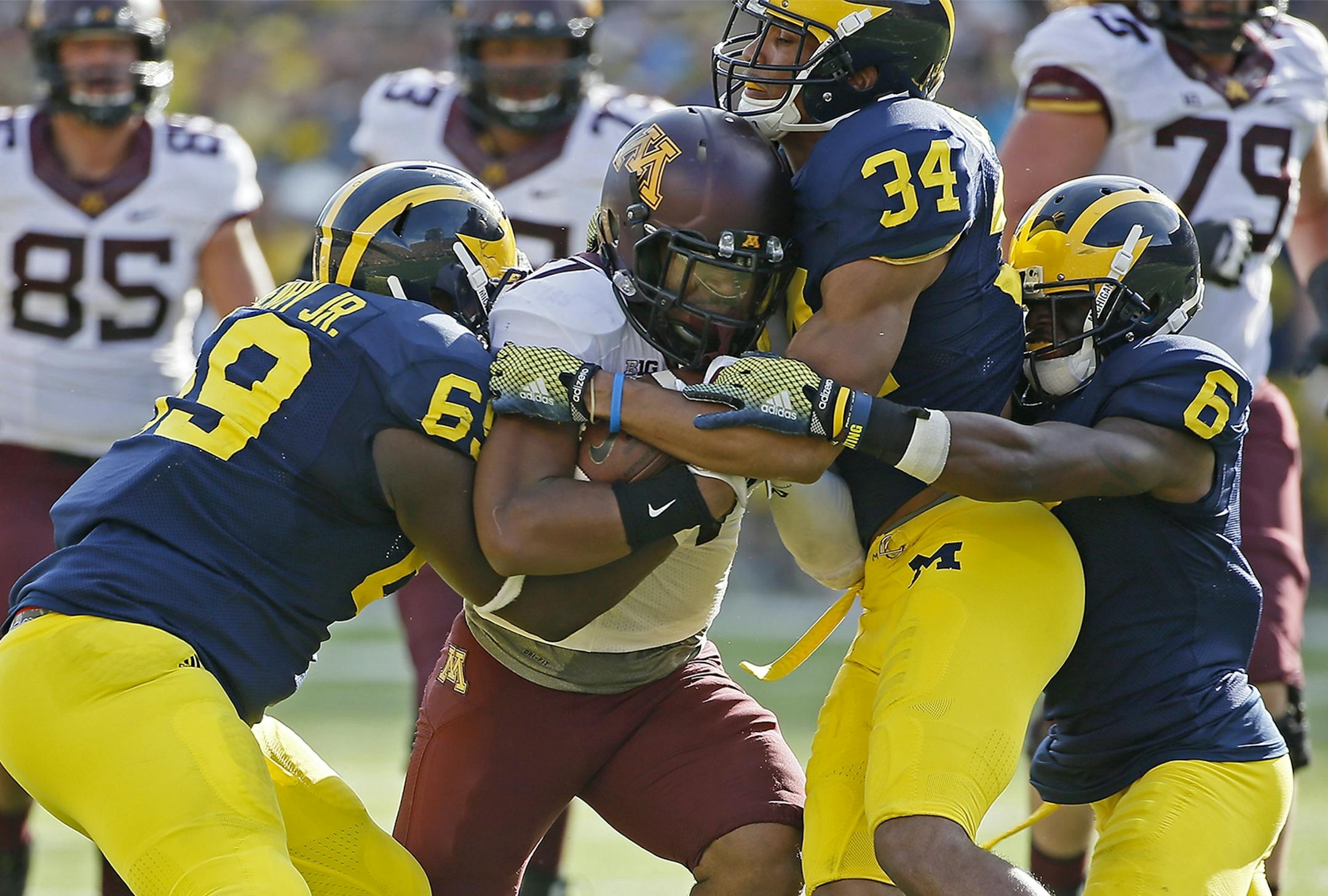 Gophers running back David Cobb (27) rushed for a first down despite pressure from Michigan defensive tackle Willie Henry (69), defensive back Jeremy Clark (34) and defensive back Raymon Taylor (6) in Minnesota's 30-14 victory Saturday in Ann Arbor, Mich.