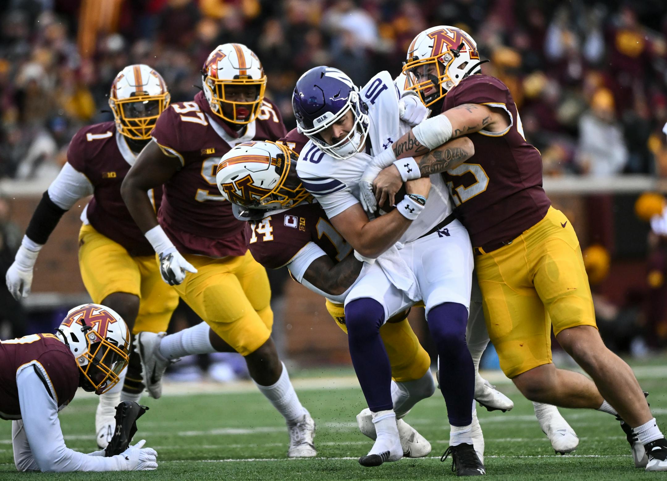 Northwestern Wildcats quarterback Brendan Sullivan (10) is sacked by Minnesota Gophers linebacker Braelen Oliver (14) and linebacker Cody Lindenberg (45) during the first half.