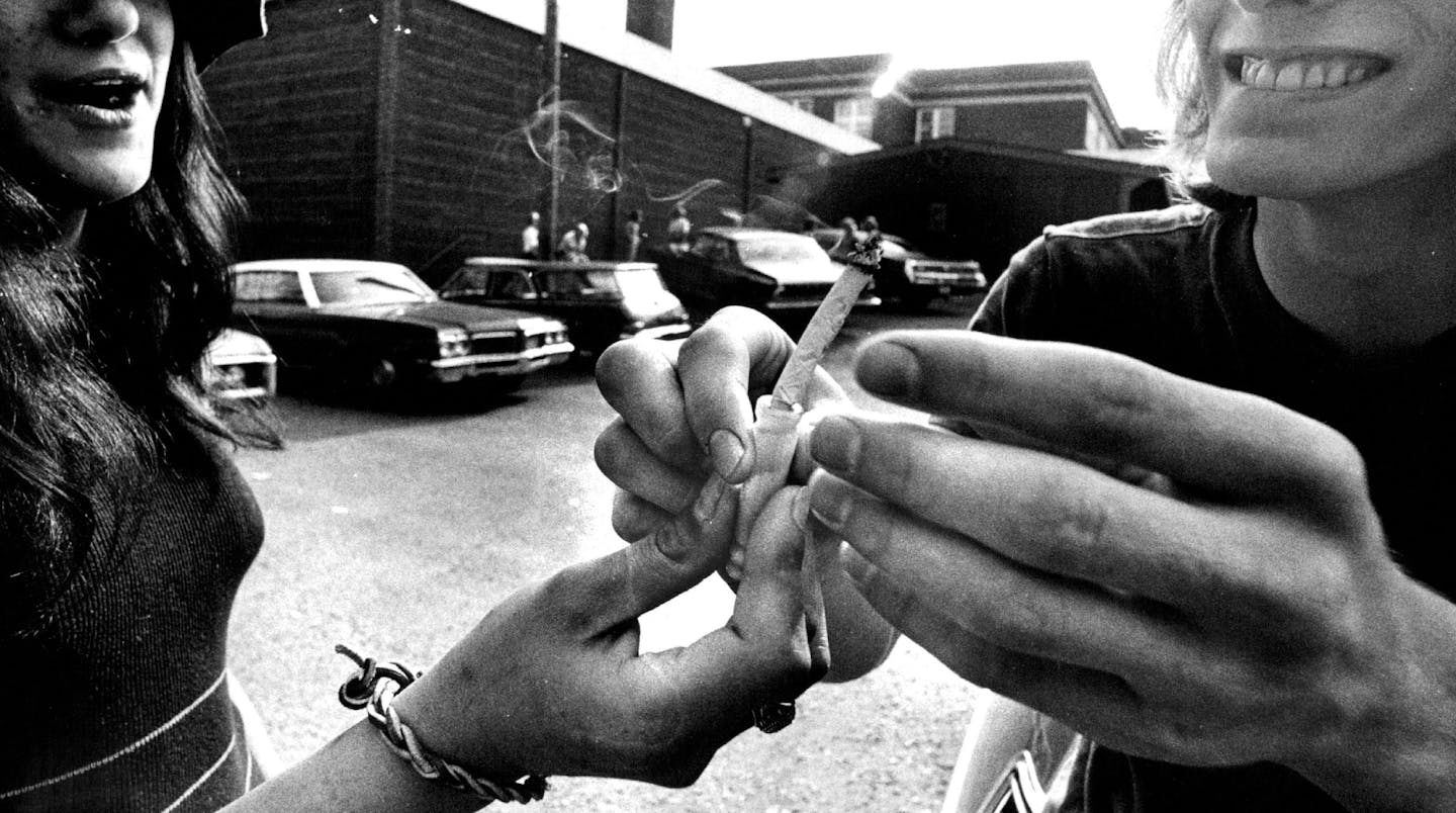 In this Star Tribune file photo, two people pass a marijuana joint outside Wayzata High School in 1977, long before recreational cannabis was legalize