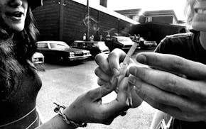 In this Star Tribune file photo, two people pass a marijuana joint outside Wayzata High School in 1977, long before recreational cannabis was legalize