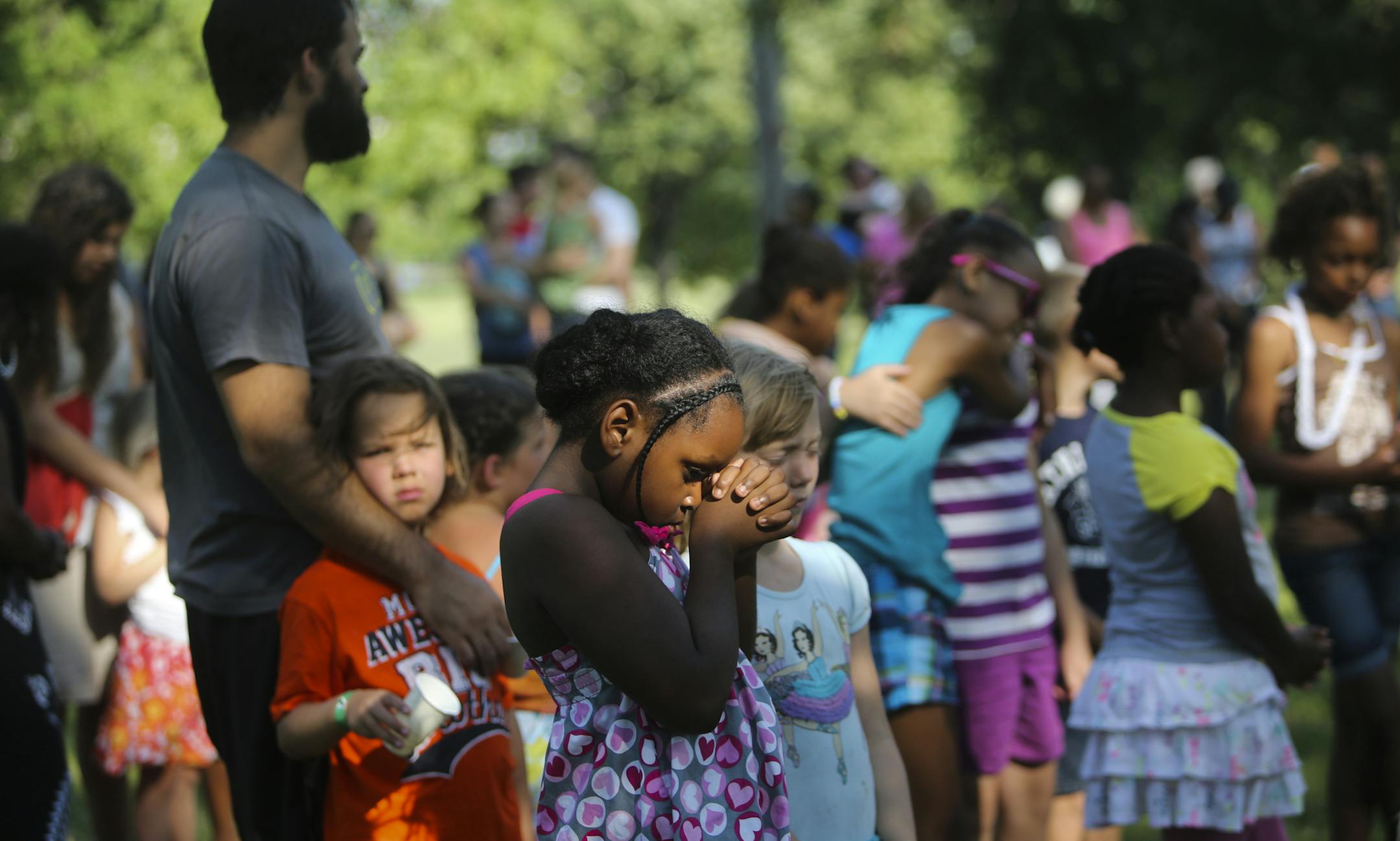 Community Covenant church member Mikayla Riddley, 7, clasped her hands together during a prayer before a picnic dinner Friday, July 12, 2013, in Minneapolis, MN. "A church is not a building. A church is a people," Rev. Luke Swanson told those gathered after a fire was started in the church Thursday night.](DAVID JOLES/STARTRIBUNE) djoles@startribune.com A string of rapid-fire arsons unfolded in a section of north Minneapolis early Friday, with a piano inside Community Covenant Church among the i