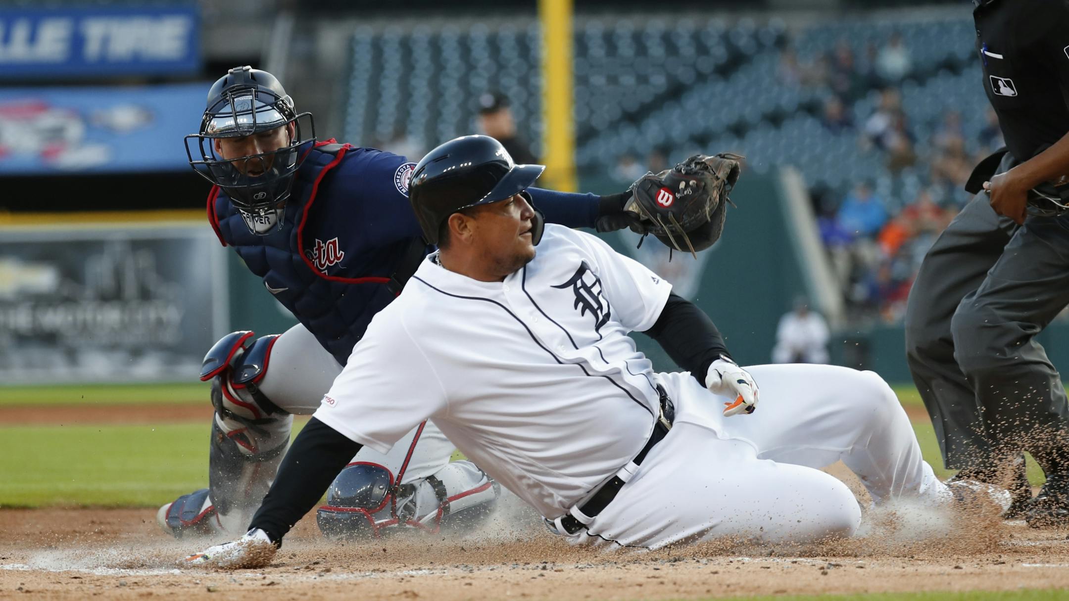 Detroit Tigers' Miguel Cabrera slides safely past the tag of Minnesota Twins catcher Mitch Garver to score at home plate in the first inning of a baseball game in Detroit, Wednesday, Sept. 25, 2019.